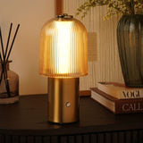 Ribbed Dome USB LED Touch Table Lamp with champagne glass shade and brushed bronze cylindrical base, lit on a dark sideboard beside books and a vase.