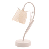 Battery LED table lamp with a cream bell-shaped floral shade on a curving stem, flanked by slender leaves and a small bud, set on a round base against a plain white background.