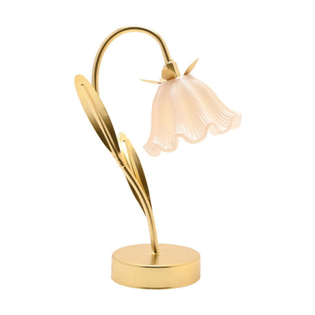 Gold floral stem LED table lamp with arching stem, two sweeping leaves, round base, and a pale blush fluted bell shade, shown on a plain white background.