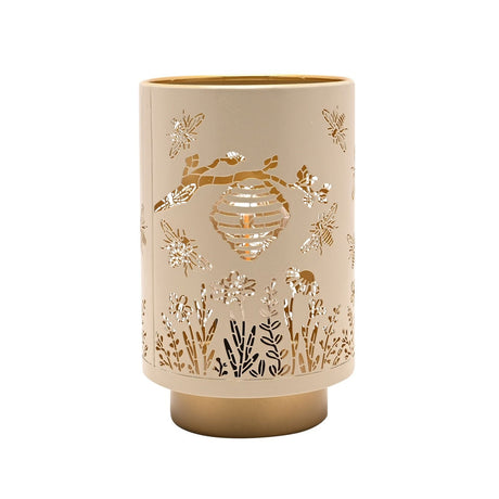 Cream cylindrical LED table lamp, 15.3cm, with cut-out bee, honeycomb and wildflower design on a gold base, gold interior, shown on a plain white background.