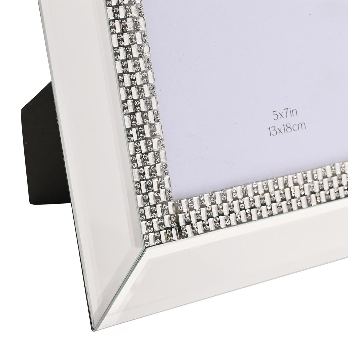 Close-up of a rectangular mirrored glass photo frame with bevelled silver edges and a diamante band of square and round stones, shown with its stand, for a 5x7in photo.