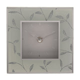 Square mantel clock with a grey square dial, baton markers, and silver hands, framed by a glitter leaf motif on a glass-effect grey border.