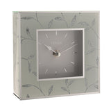 Square mantel clock with a grey dial and silver baton markers, framed by a pale border and glass sides decorated with silver glitter leaf stems, shown on a plain white background.