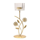 Gold metal single candle holder with floral leaf stem design and round base, topped with a clear ribbed glass tea light cup, on a plain white background.