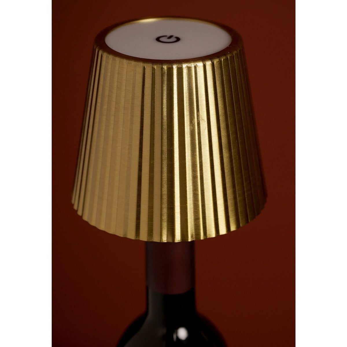 Wine bottle topper LED table lamp with a gold pleated tapered shade, white top touch control, and ridged stopper, shown fitted onto a dark bottle neck.