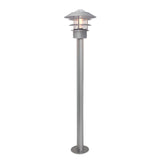 The Helsingor 1 Light Bollard Lantern in silver showcases Scandinavian design with its modern aesthetics, featuring a round, tiered lampshade and a visible light bulb. It's mounted on a sturdy cylindrical base, making it an ideal outdoor lighting fixture.