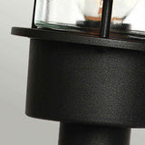 Close-up of the black Helsingor 1 Light Pedestal Light with a glass enclosure. The image captures the upper section, highlighting its textured metal surface—an embodiment of Scandinavian design in outdoor lighting.