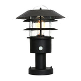 The Helsingor 1 Light PIR Pedestal Light in black has a modern design with a cylindrical base, glass enclosure, and layered circular metal shades. Its visible bulb through the clear glass enhances its aesthetic on a white background, perfectly balancing style with security lighting functionality.