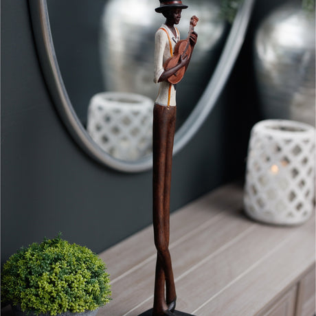 Hill Interiors Nerisse figurine of a tall, slim jazz musician in hat playing guitar, bronze and copper resin finish, styled on a console beside a mirror.