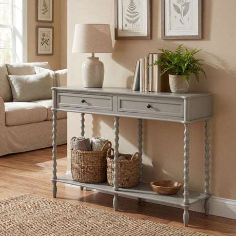 Hill Interiors Halvorne Large Two Drawer Console Table in grey with turned legs and lower shelf, styled with a lamp, books and baskets in a living room.