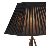 Close-up of the Hilton 1 Light Large Wood Table Lamp in black and grey with a pleated black shade. Soft light glows through the vertical stripes, accentuating the lamp's textured design and modern style.
