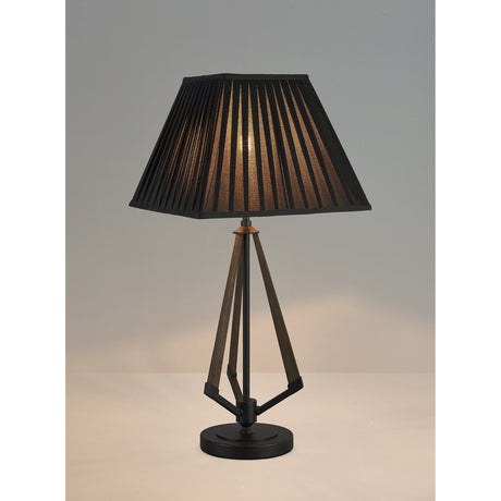 The Hilton 1 Light Large Wood Table Lamp features a black and grey base with a black shade, casting a warm glow on a light surface and standing out elegantly against a plain background.