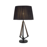 The Hilton 1 Light Small Wood Table Lamp features a black and grey base with a black shade, offering a modern, minimalist look. Its warm light glows softly through the pleated shade, perfect for accent lighting in any space.