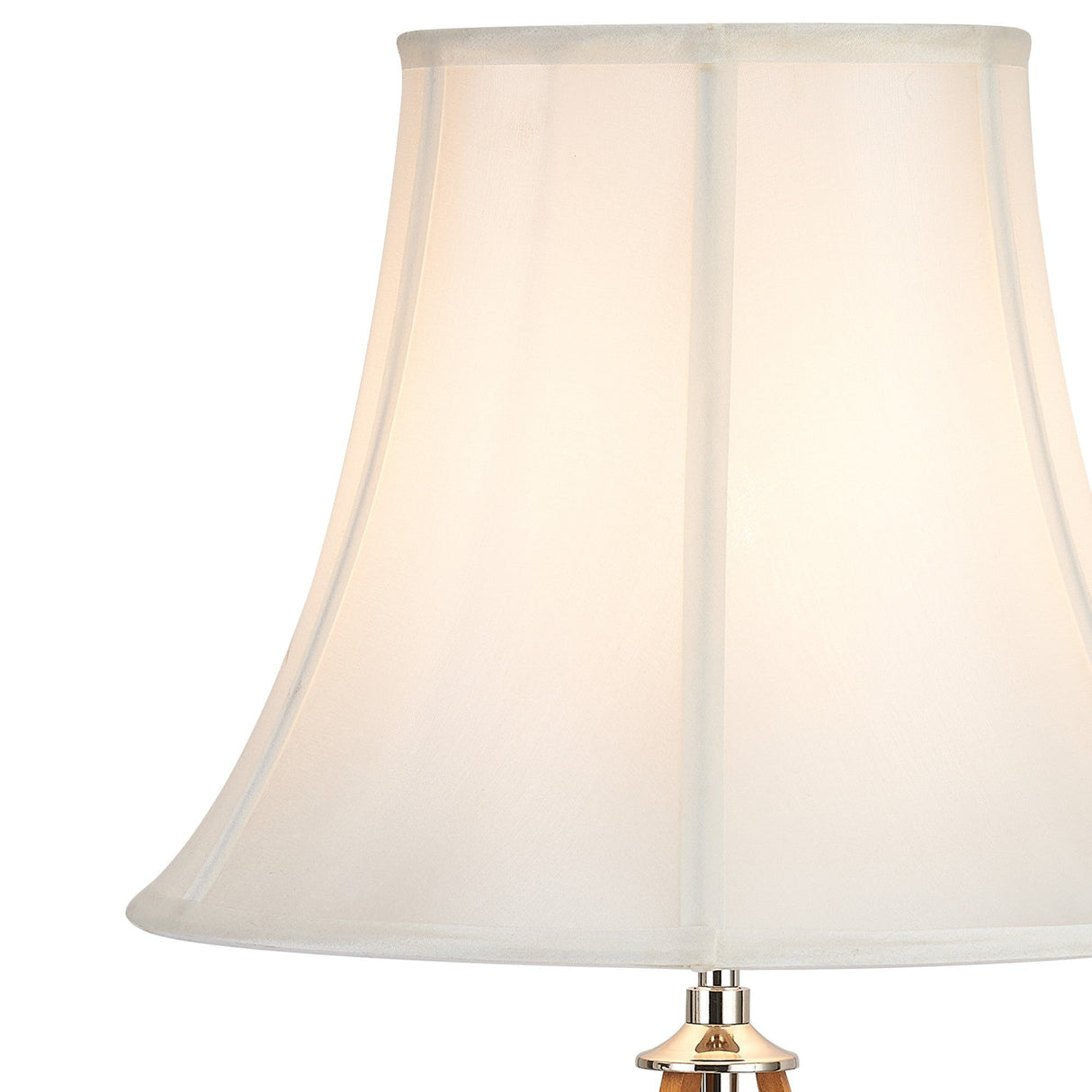 A close-up of the Hilton 1 Light Wood Table Lamp in nickel and taupe, featuring a cream, slightly flared fabric shade softly glowing with light, with part of its gold-colored base visible.