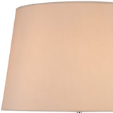 Close-up of the Hilton 1 Light Wood Table Lamp in nickel and taupe, featuring a nude beige shade. Soft, warm lighting highlights the top of the elegant lampshade against a white background.