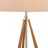 Close-up of the Hilton 1 Light Wood Table Lamp in nickel and taupe, featuring a central metal rod and three wooden legs forming a tripod base with a nude beige shade. Its modern design adds elegance to any space.