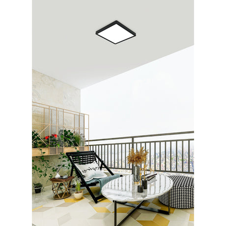 Hinanne LED Downlight, 28.5 x 28.5cm square flush ceiling fitting with black steel frame and white diffuser, shown on a balcony ceiling above a seating area.