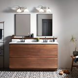 A modern bathroom showcases a wooden vanity with a white countertop paired with twin black faucets. Above the vanity, two rectangular mirrors are complemented by polished chrome Ainsley 2 Light Wall Lights featuring LED lamps. The space is adorned with a small plant and toiletries, while patterned tiles cover the floor.
