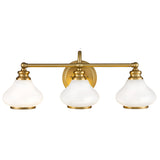 The Ainsley 3 Light Wall Light in brushed brass is a stylish vanity fixture with a central wall mount. It includes three opal glass shades, each in a bell shape, evenly distributed along a horizontal bar for a timeless and sophisticated appearance.