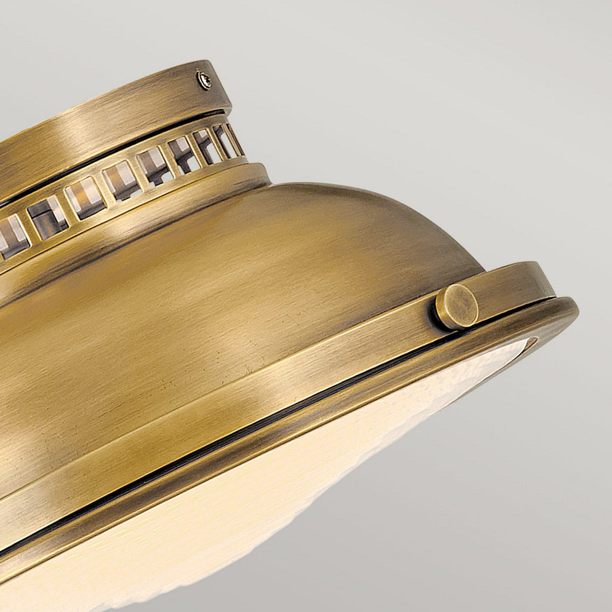 A close-up of the Amelia 2 Light Flush Light - Brass highlights its vintage aesthetics with intricate cut-out details along the top edge. The brass finish on the domed design gleams elegantly, featuring a small knob on the side, set against a subtle light gray backdrop.
