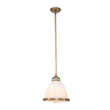 The Amelia 1 Light Medium Pendant - Brass exudes vintage charm with its dome-shaped, frosted glass shade. Hanging from the ceiling, its minimalist design is elegantly showcased through a slender rod connecting the ceiling mount to the fixture, making it a perfect fit for any modern farmhouse decor.