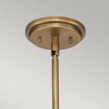 Close-up of the "Amelia 1 Light Medium Pendant - Brass" showcasing a brushed brass finish with vintage charm, featuring a cylindrical rod extending downwards. The pendant includes a round base that enhances its modern farmhouse appeal, set against a light gray background.