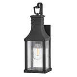 The Beacon Hill 1 Light Outdoor Small Wall Lantern in Black boasts a rectangular design with a clear seeded glass enclosure. Inside, it displays a single visible bulb and is elegantly topped with a decorative loop.