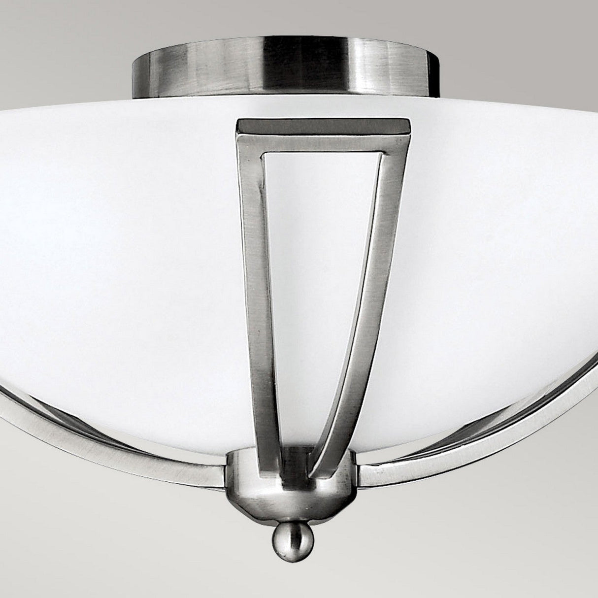 A close-up of the Bolla 2 Light Flush fixture, featuring a frosted glass shade and an angular brushed nickel frame, is set against a plain gray background, highlighting its sleek and sophisticated design.