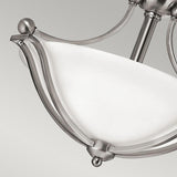 The Bolla 2 Light Semi Flush - Brushed Nickel chandelier is a stunning piece of elegant home decor, showcasing a frosted white glass bowl, brushed nickel metal accents with curved arm supports, all set against a plain gray background.