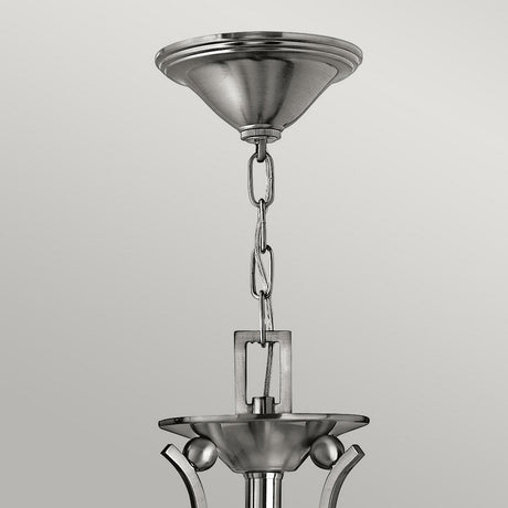A detailed view of the Bolla 3 Light Chandelier in brushed nickel, showcasing its chain link suspension and sleek, modern design with a conical ceiling mount.