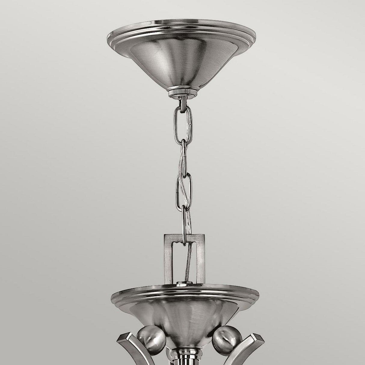 Close-up of the Bolla 5 Light Chandelier's brushed metal chain and two connecting ceiling mounts, showcasing a modern and sleek design. The Brushed Nickel finish enhances this elegant lighting fixture's minimalist and contemporary charm against a soft gray background.