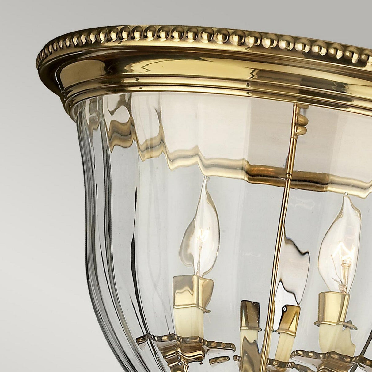 Close-up of the elegant Cambridge 3 Light Flush - Burnished Brass ceiling fixture, highlighting its classic New England style design. It includes three candle-shaped bulbs, a beaded edge, and clear glass panels, all set against a neutral background.