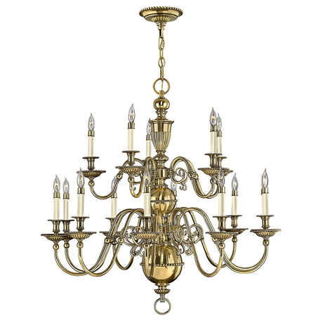 A Cambridge 15 Light Chandelier in burnished brass, featuring a large and elegant design, hangs from a chain. Its multiple arms hold candle-shaped lights, with intricate and ornate detailing along with a polished finish that evokes a classic and sophisticated style.