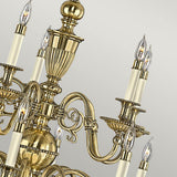 A detailed view of the Cambridge 15 Light Chandelier - Burnished Brass, highlighting its elegant scrollwork in a burnished brass finish. The chandelier includes numerous candle-style bulbs encased in clear glass, all set against a light gray background.
