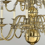 A detailed view of the Cambridge 15 Light Chandelier - Burnished Brass highlights its elaborate burnished brass finish with intricate scrollwork. Each gracefully curved arm holds multiple candle-style bulbs, set against a neutral background that accentuates its lustrous, reflective surface.