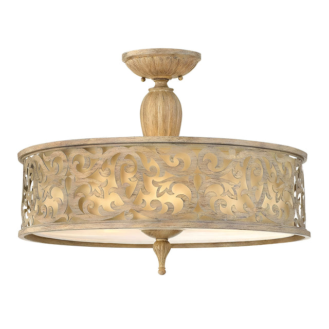 The Carabel 3 Light Large Semi Flush in a brushed champagne finish features an ornate, patterned metal exterior with intricate scrollwork. It emits a warm glow through its translucent diffuser at the bottom, making it perfect for your semi flush lighting needs.