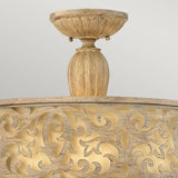 The Carabel 3 Light Large Semi Flush in Brushed Champagne boasts ornate gold and wood-toned details with intricate vine-like patterns and a rounded base. Complemented by ivory linen shades, this lighting fixture shines against a neutral gray background, adding a sophisticated touch to any space.