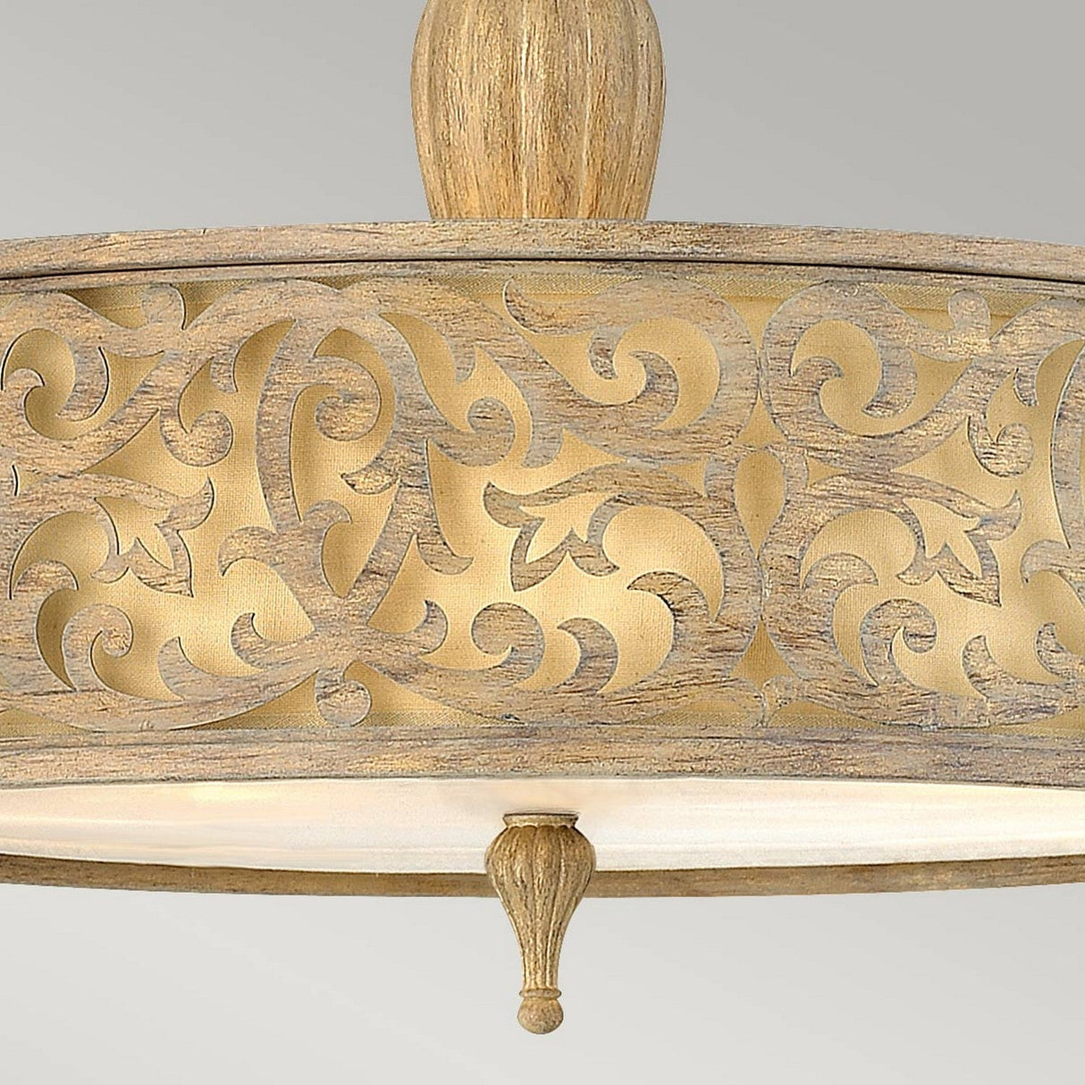 The Carabel 3 Light Large Semi Flush – Brushed Champagne showcases a detailed wooden ceiling light fixture with an ornate design. It features intricate swirling patterns, and the semi flush lighting softly illuminates its surroundings, casting delicate shadows over the craftsmanship.