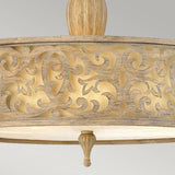 The Carabel 3 Light Large Semi Flush – Brushed Champagne showcases a detailed wooden ceiling light fixture with an ornate design. It features intricate swirling patterns, and the semi flush lighting softly illuminates its surroundings, casting delicate shadows over the craftsmanship.