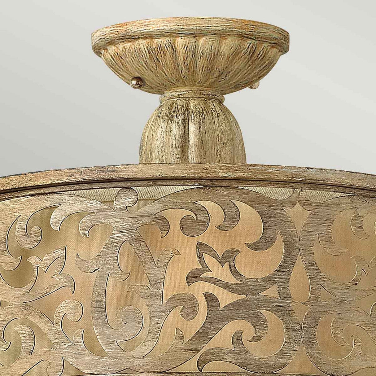 A close-up of the Carabel 2 Light Small Semi Flush in Brushed Champagne, showcasing its intricate golden floral patterns on a circular base. The brushed champagne finish enhances its rustic, vintage charm and adds an elegant touch to the decor.