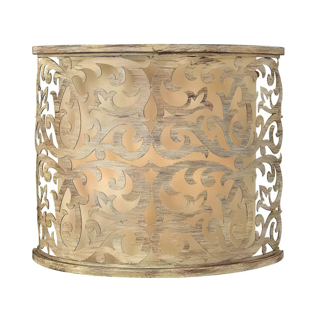 The Carabel 2 Light Wall Light - Brushed Champagne features a cylindrical design adorned with detailed pierced metalwork. Its brushed champagne finish gives it a vintage look, while the light gently diffuses through the patterned shade, bringing sophistication to any space.