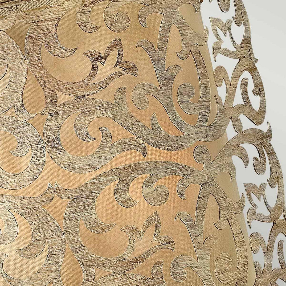 Close-up of an intricate decorative pattern featuring swirling, metallic gold designs on a warm beige background, reminiscent of the Carabel 2 Light Wall Light's brushed champagne finish. The ornate scrollwork boasts a textured finish akin to pierced metalwork artistry.