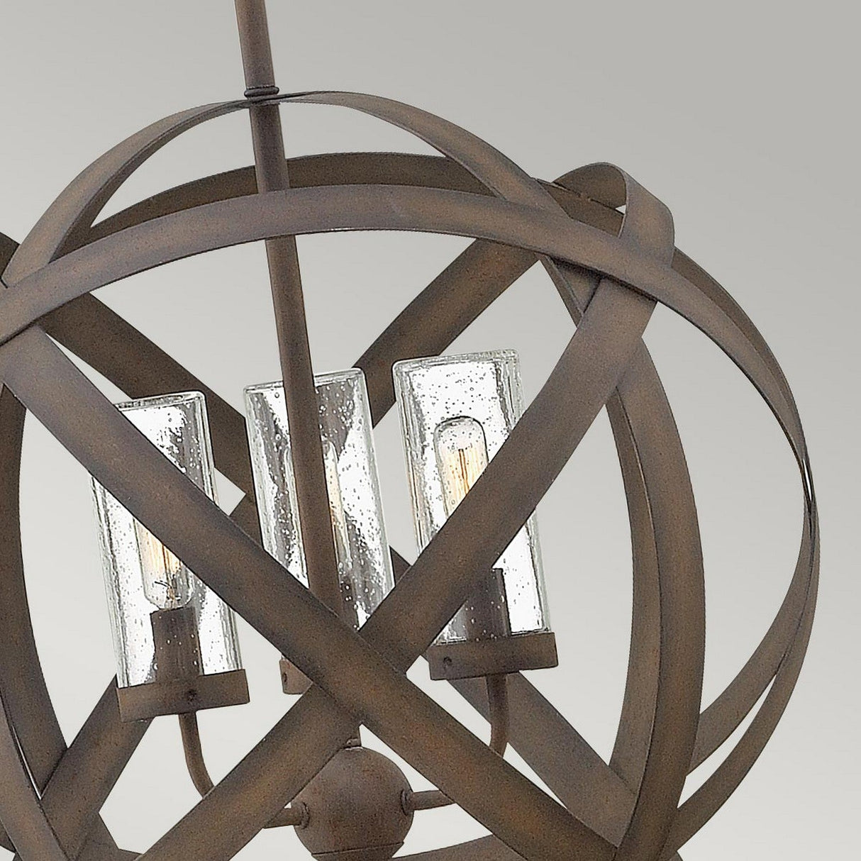 Close-up of the Carson 3 Light Outdoor Chandelier - Vintage Iron, showcasing three glass bulb holders within an intertwined, spherical metal frame. The vintage iron finish adds a touch of rustic charm against the neutral gray background.