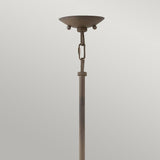 The Carson 5 Light Outdoor Chandelier in Vintage Iron boasts a rustic charm with its tall, slender design featuring a circular, bowl-shaped top and two spherical accents. It is set against a plain light gray background.