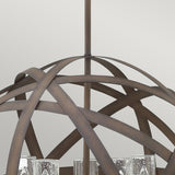 The Carson 5 Light Outdoor Chandelier in Vintage Iron features an orb-shaped metal frame with several candle-style light fixtures. The lights are turned off, highlighting the fixture's vintage iron elegance and showcasing its rustic charm.