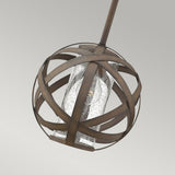 The Carson 1 Light Outdoor Pendant Light - Vintage Iron features a spherical design with dark metal bands surrounding a clear textured glass cylinder. Ideal for outdoor areas, it holds a single bulb and hangs gracefully against a plain gray backdrop.