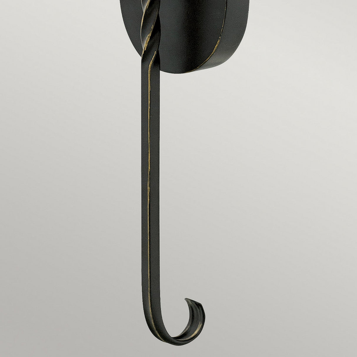 The Casa 1 Light Wall Light - Black features a unique twisted design with a long, curved end, enhancing the wrought iron structure. Its smooth matte finish creates a striking contrast against plain, light-colored backgrounds.