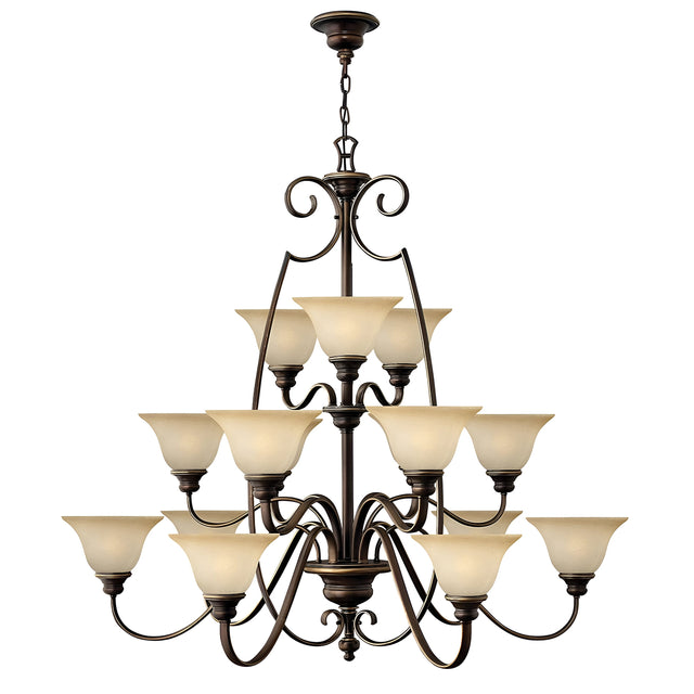 The Cello 15 Light Chandelier in Antique Bronze is a large and elegant fixture with two tiers of vintage faux alabaster glass lampshades. It features intricate scrollwork details and is suspended from a decorative chain.