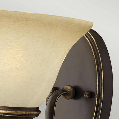 Close-up of the Cello 1 Light Wall Light - Antique Bronze, showcasing its frosted glass shade and antique bronze base. The design is simple and elegant, with emphasis on the upper edge of the shade and a portion of the mounting hardware that conveys a vintage charm.