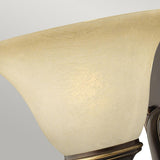 The Cello 1 Light Wall Light - Antique Bronze showcases a close-up view of its cream-colored, vintage faux alabaster glass shade, elegantly mounted on an antique bronze base. Its tulip-shaped design faces upward against a light gray background.